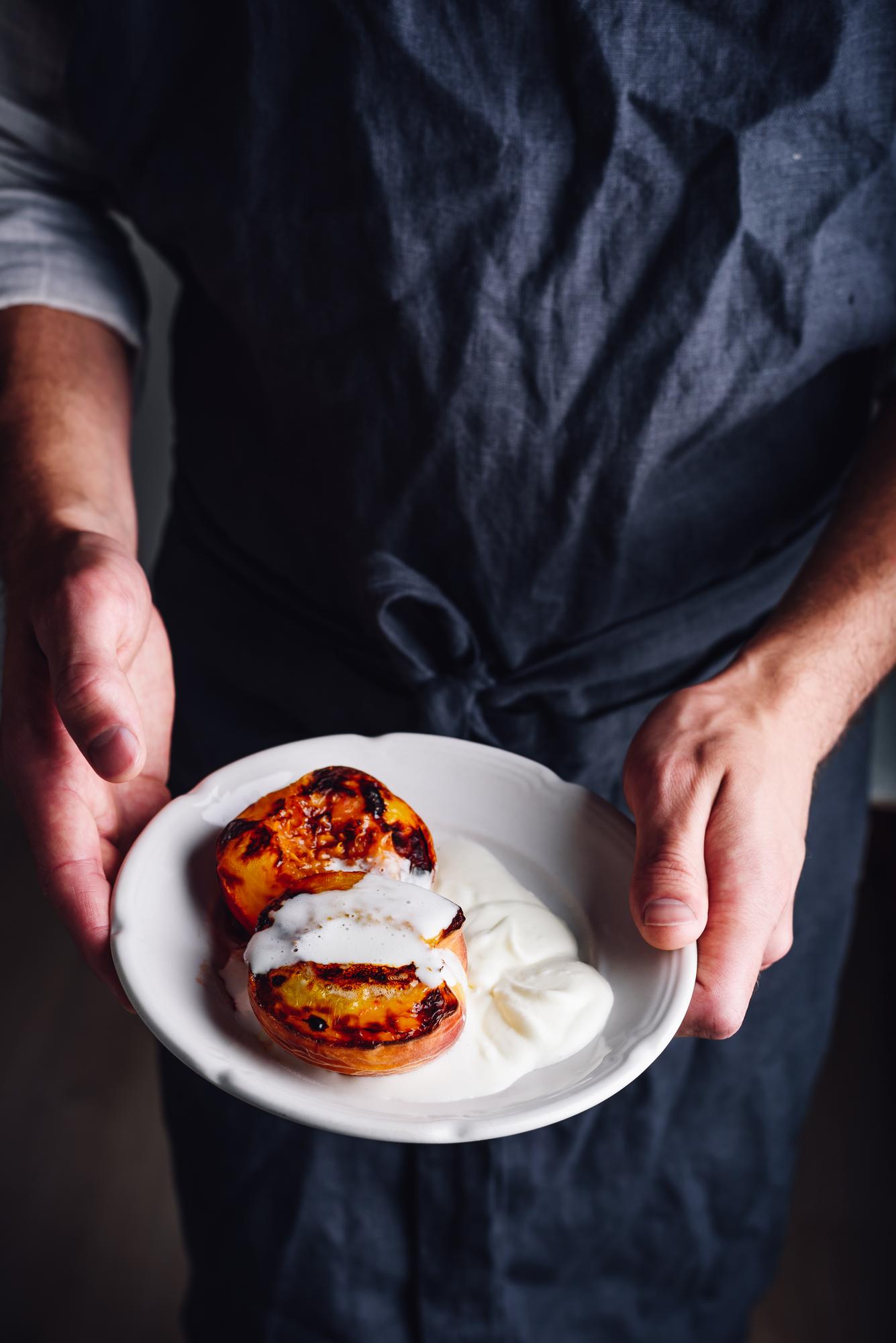 Instructor plating a composed dish in warm kitchen
